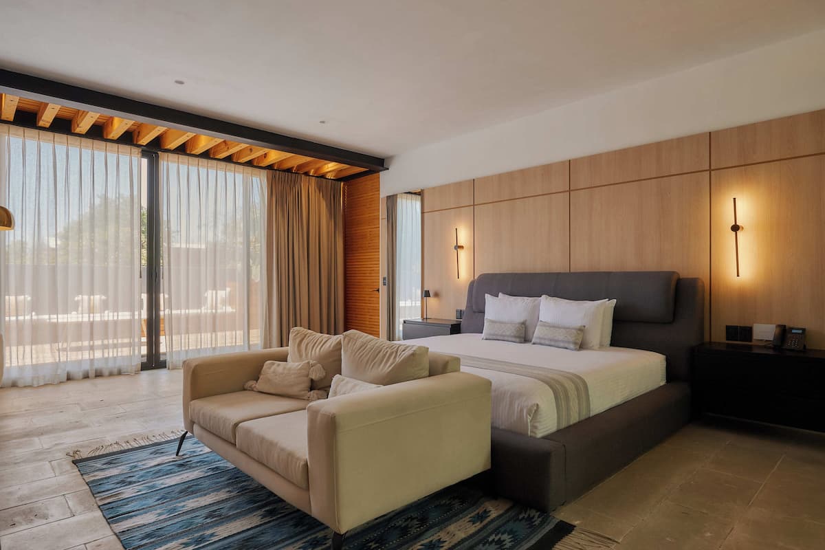 A modern bedroom with a large bed, a sofa, and a nightstand.