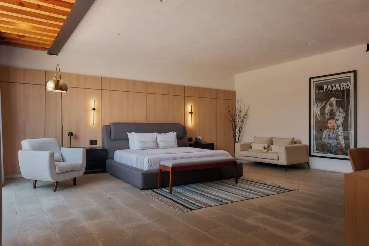 A modern bedroom with a large bed, bedside tables, a chair, and a poster on the wall.