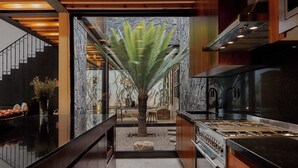 A modern kitchen with a central island, built-in appliances, and a stone wall backdrop. - Casa Carmen Xólotl (Oaxaca)