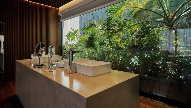 A modern bathroom with a large window, a wooden ceiling, and a sink with a mirror. - Casa Carmen Xólotl (Oaxaca)