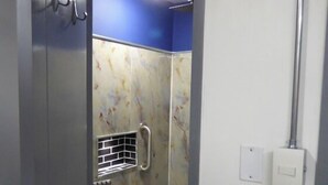 Un baño pequeño con cabina de ducha, barras de apoyo y suelo de azulejos.