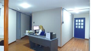 Un mostrador de recepción con una computadora, un teléfono y una persona sentada detrás.