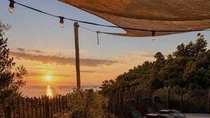An outdoor dining area with a round table, chairs, and a sunset view. - Mare è Machja RDC • Sea view - Heated swimming pool - 6 people (Sari-Solenzara)