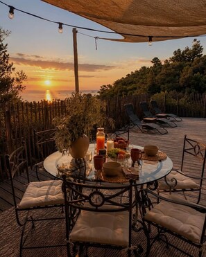 Un área de comedor al aire libre con una mesa redonda, sillas y vistas al atardecer.