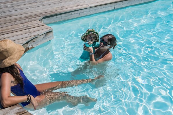 Une piscine dotée d’une terrasse en bois et d’une eau d’un bleu cristallin.