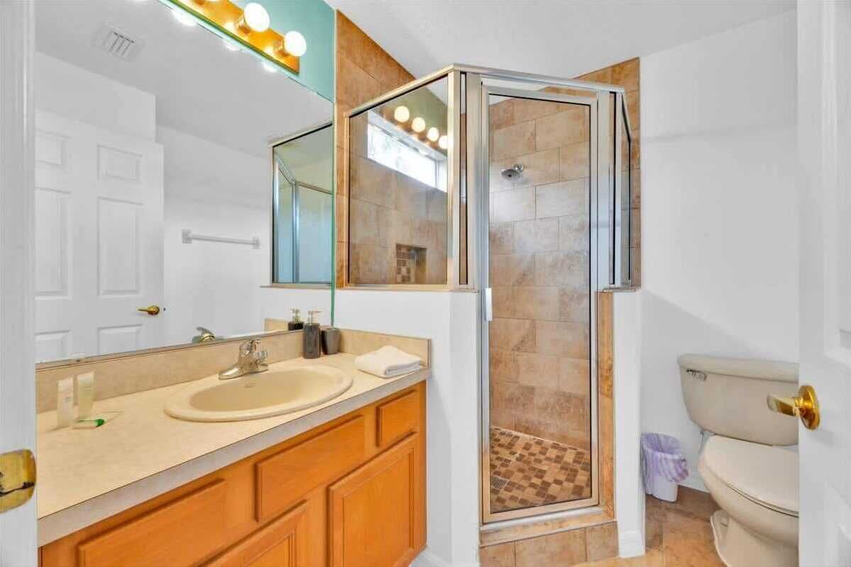 Un bany modern amb dutxa envidriada, un mirall gran i un lavabo beix.