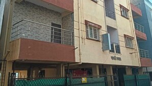 A multi-story building with balconies, a gated entrance, and a sign indicating a commercial use.