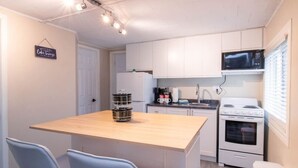 Una cucina compatta con mobili bianchi, un'isola in legno e un forno a microonde.