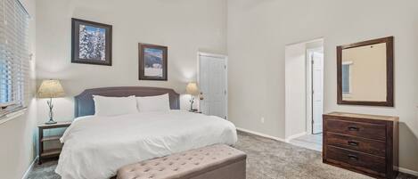 A bedroom with a bed, bench, dresser, and ceiling fan.