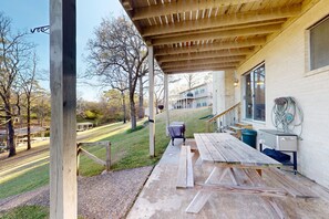 Un espacio al aire libre techado con mesas de picnic y una parrilla.