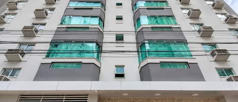Un edificio de varios pisos con un diseño arquitectónico moderno, que cuenta con una serie de balcones y unidades de aire acondicionado.