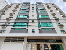 Edifício de vários andares com design arquitetônico moderno, apresentando uma série de varandas e aparelhos de ar condicionado.