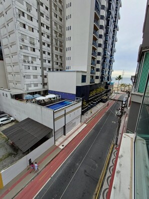 A multi-story residential building with balconies, a covered outdoor seating area, and a street with a red bike lane. - Ap Vista Mar - Ed Belo Mar - BC (Balneário Camboriú)