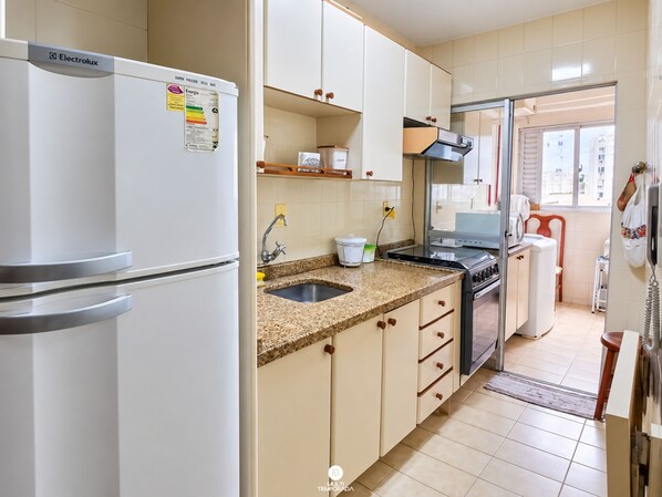 A kitchen with a refrigerator, stove, sink, and cabinets. - Ap Vista Mar - Ed Belo Mar - BC (Balneário Camboriú)