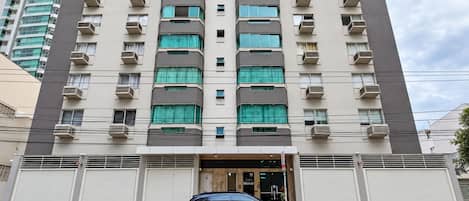 Un edificio de varios pisos con un estacionamiento en la parte delantera.