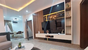 A modern living room with a sofa, coffee table, and TV stand. - 989 Apartments (Abuja)