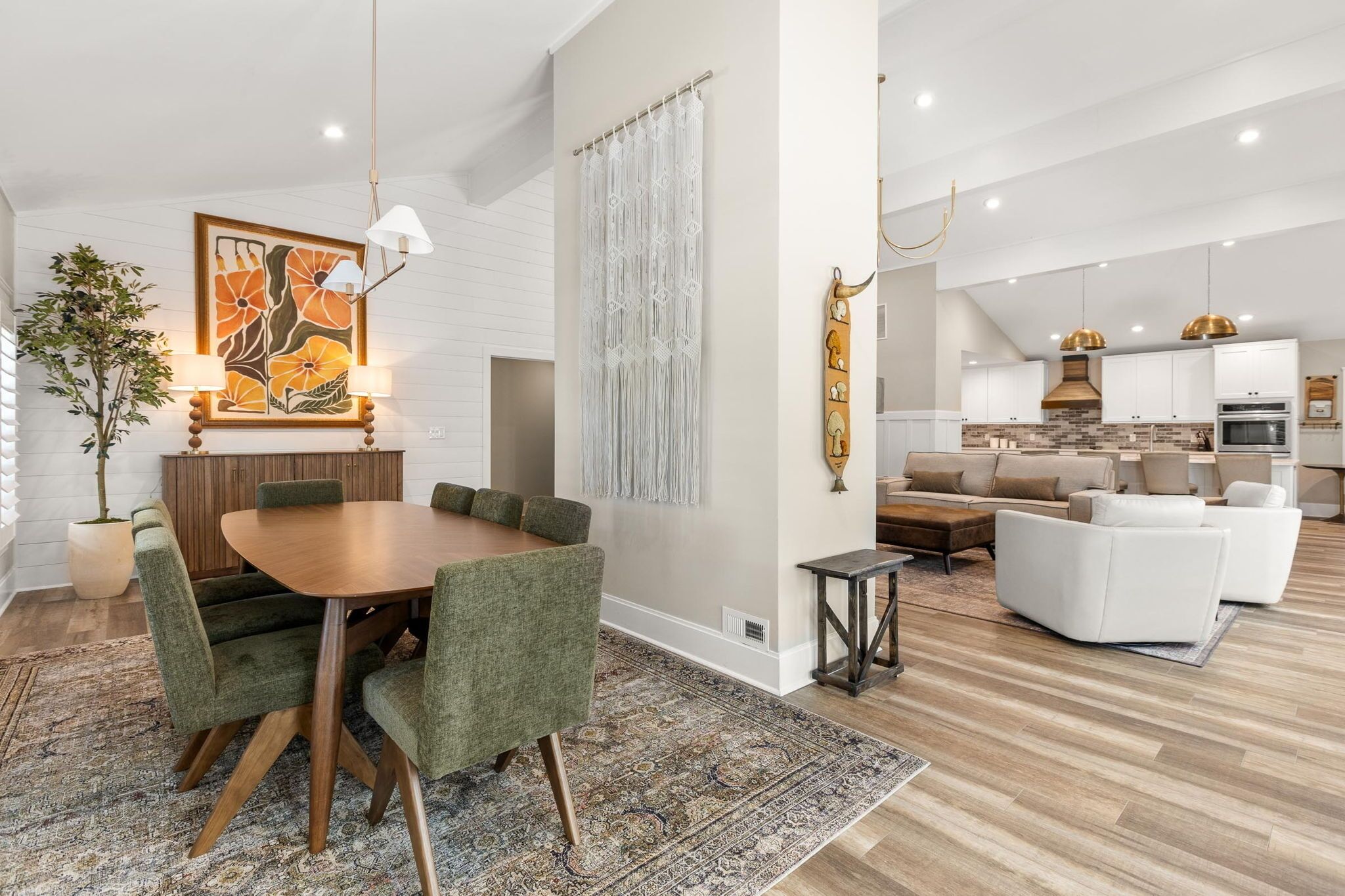 A modern living room with a dining area, a kitchen, and a staircase.