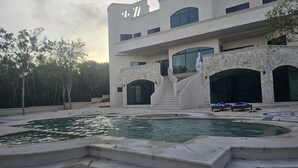 Un edificio moderno con piscina, arcos de piedra y una escalera que conduce a la entrada.