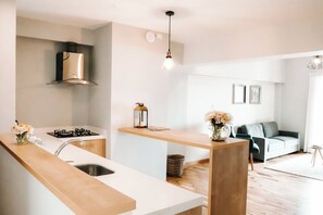 Una cocina moderna con una isla central, estufa integrada y una lámpara colgante.
