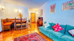 Ein Wohnzimmer mit einer Couch, einem Esstisch mit Stühlen, einem Holzschrank und einem Teppich.