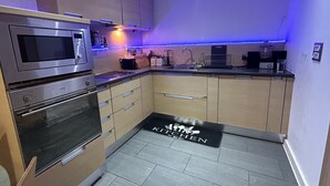 Ett modernt kök med vitvaror i rostfritt stål, en inbyggd mikrovågsugn och ett brödhylla.