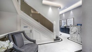 Un vestíbulo moderno con una escalera, un mostrador de recepción y una zona de estar.