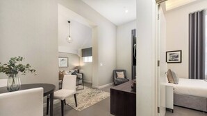Une chambre d’hôtel moderne comprenant un coin repas, un espace salon avec un canapé et des fauteuils, un bureau et un lit.