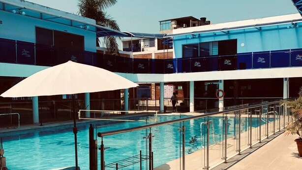 Une piscine à l’eau d’un bleu limpide, entourée d’une terrasse carrelée et agrémentée de parasols.