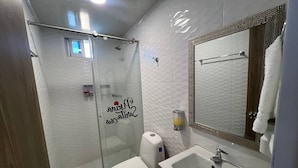 Une salle de bain avec une douche à parois de verre, des toilettes, un lavabo et un miroir.