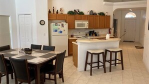 Una cocina moderna con armarios de madera, una isla central y un comedor con mesa y sillas.