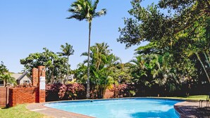 A swimming pool surrounded by lush greenery and a brick wall. - Villa Mia - Two Bedroom Apartment, Sleeps 4 (Saint Lucia)