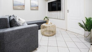 A modern living room with a grey sofa, a round wicker coffee table, and a potted plant. - Villa Mia - Two Bedroom Apartment, Sleeps 4 (Saint Lucia)