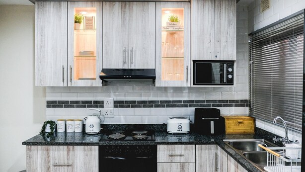 A modern kitchen with wooden cabinets, a black stove, a microwave, and a sink. - Villa Mia - Two Bedroom Apartment, Sleeps 4 (Saint Lucia)