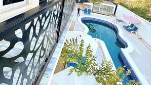 Un balcon d’habitation avec une piscine, une vue sur les environs et une rambarde décorative.