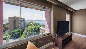 A modern living room with a large window, a flat-screen TV, and a wooden entertainment unit.
