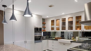 A modern kitchen with white cabinets, a marble countertop, and a fruit basket.