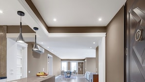A spacious kitchen with a marble countertop, pendant lighting, and a view into the dining area.