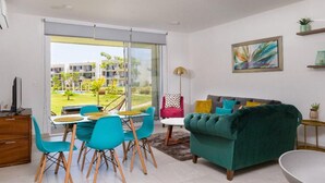 A modern living room with a green sofa, teal chairs, and a dining table. - Serenity Escape (Mezcales)