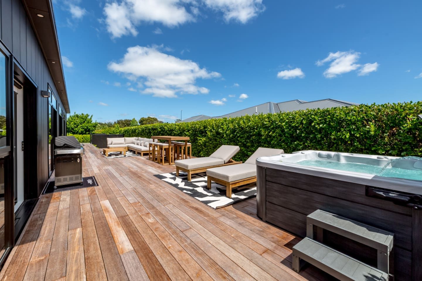 A wooden deck with outdoor furniture, a hot tub, and a view of a mountain.