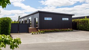 A modern building with a dark facade, large windows, and a gated entrance. - Sotally Tober Luxury Retreat | New Build, Spa, Walk to Square (Martinborough)