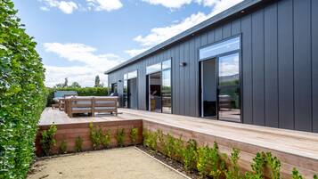 A modern building with a deck, outdoor seating, and a garden area.