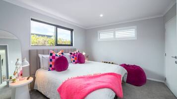 A bedroom with a bed, bedside tables, a window, and a door.