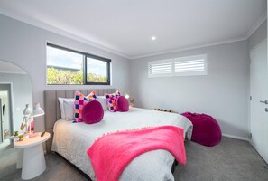 A bedroom with a bed, bedside tables, a window, and a door. - Sotally Tober Retreat (Martinborough)