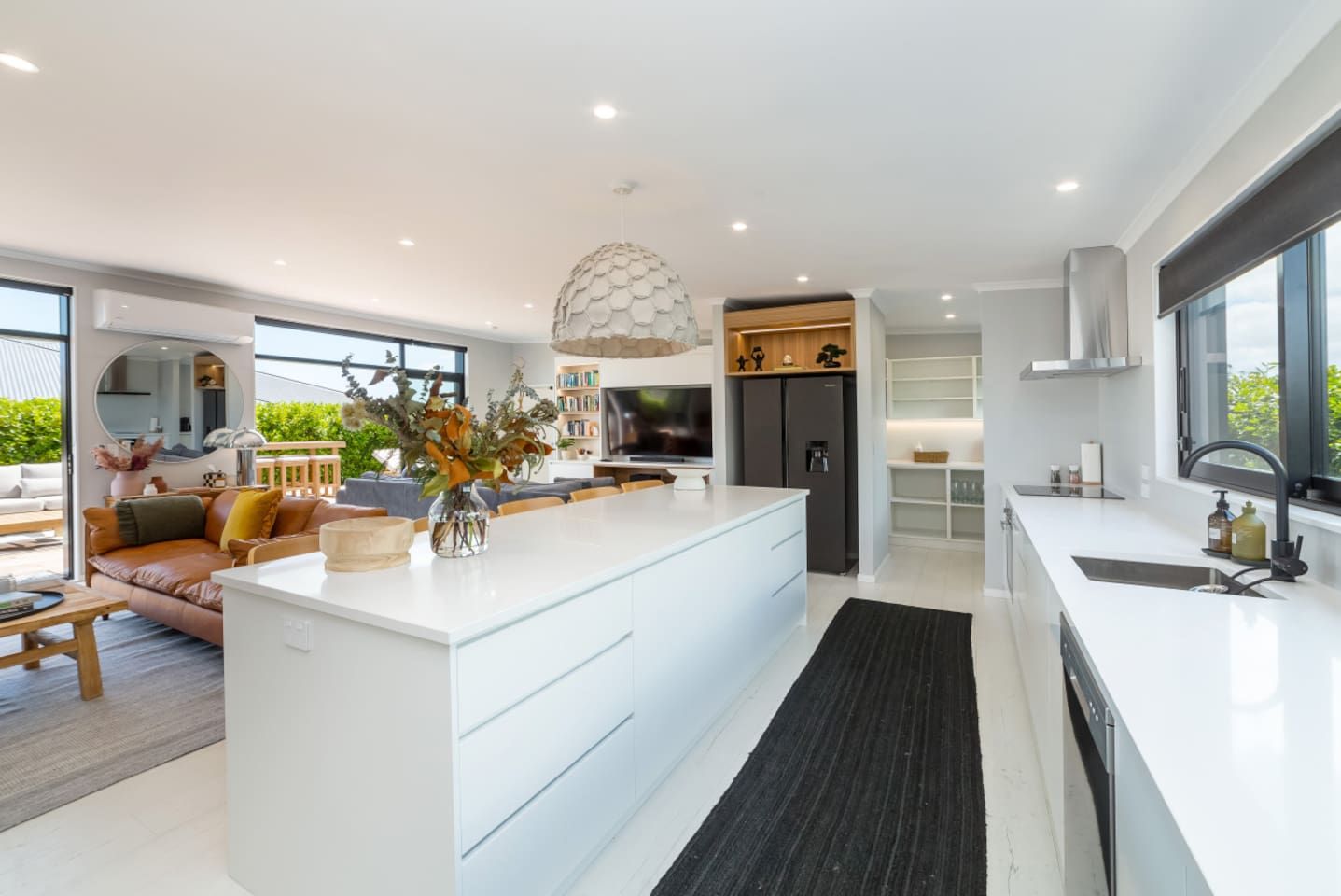 Una cocina moderna con una isla central, electrodomésticos integrados y un amplio ventanal.