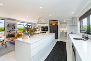 A modern kitchen with a central island, built-in appliances, and a large window.