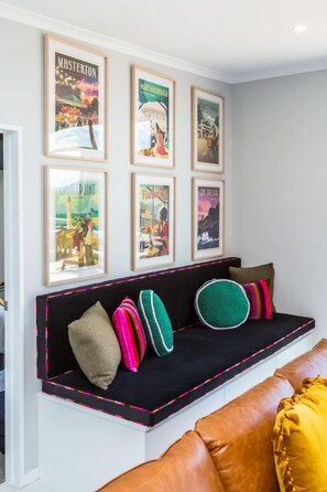 A black sofa with colorful pillows and a black-framed picture above it. - Sotally Tober Retreat (Martinborough)