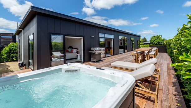 A modern house with a hot tub, outdoor seating, and a deck. - Sotally Tober Luxury Retreat | New Build, Spa, Walk to Square (Martinborough)