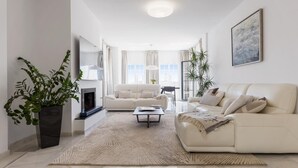 A modern living room with a fireplace, two sofas, a coffee table, and a large potted plant. - Apartment in Aldea Blanca for 6 persons |Nueva Andalucía (Nueva Andalucía)