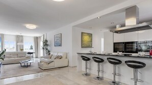 A modern apartment with a living room, kitchen, and bar area. - Apartment in Aldea Blanca for 6 persons |Nueva Andalucía (Nueva Andalucía)