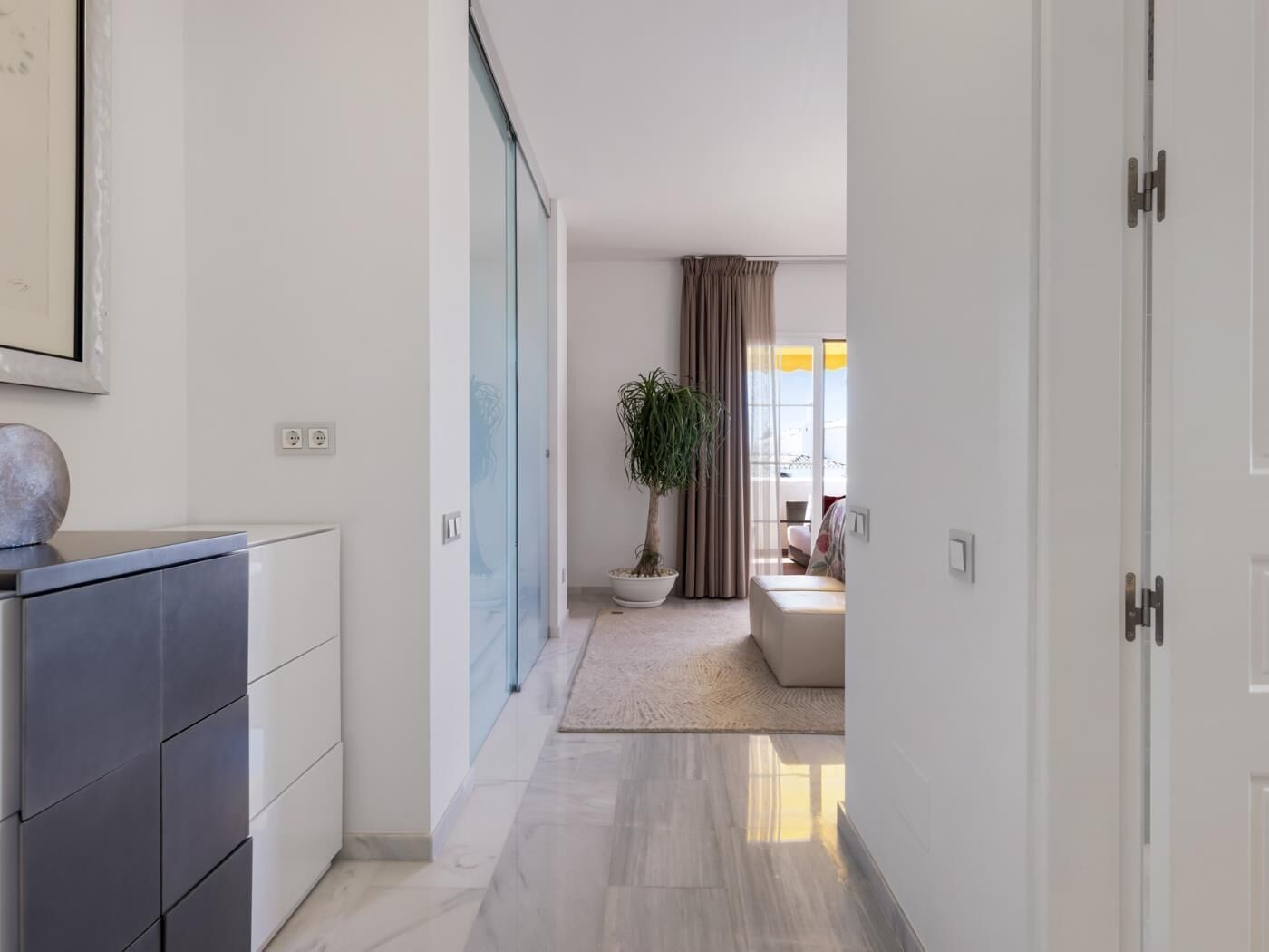Un pasillo moderno con una puerta de vidrio corredera que da a una sala de estar.